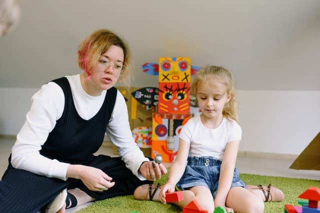 An educator playing with a child using colourful wooden blocks