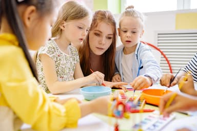 An educator guiding children through a watercolour painting activity